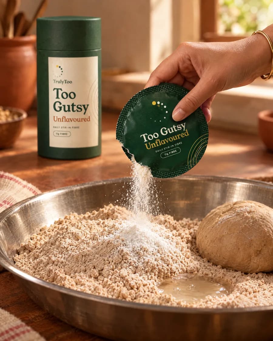 Fine white powder from a sachet being sprinkled over atta in a steel parat