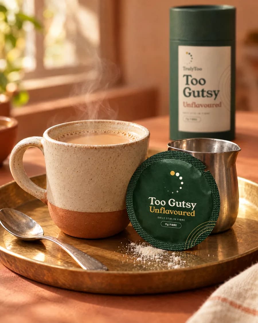 A cup of masala chai on a brass tray beside an opened Unflavoured sachet